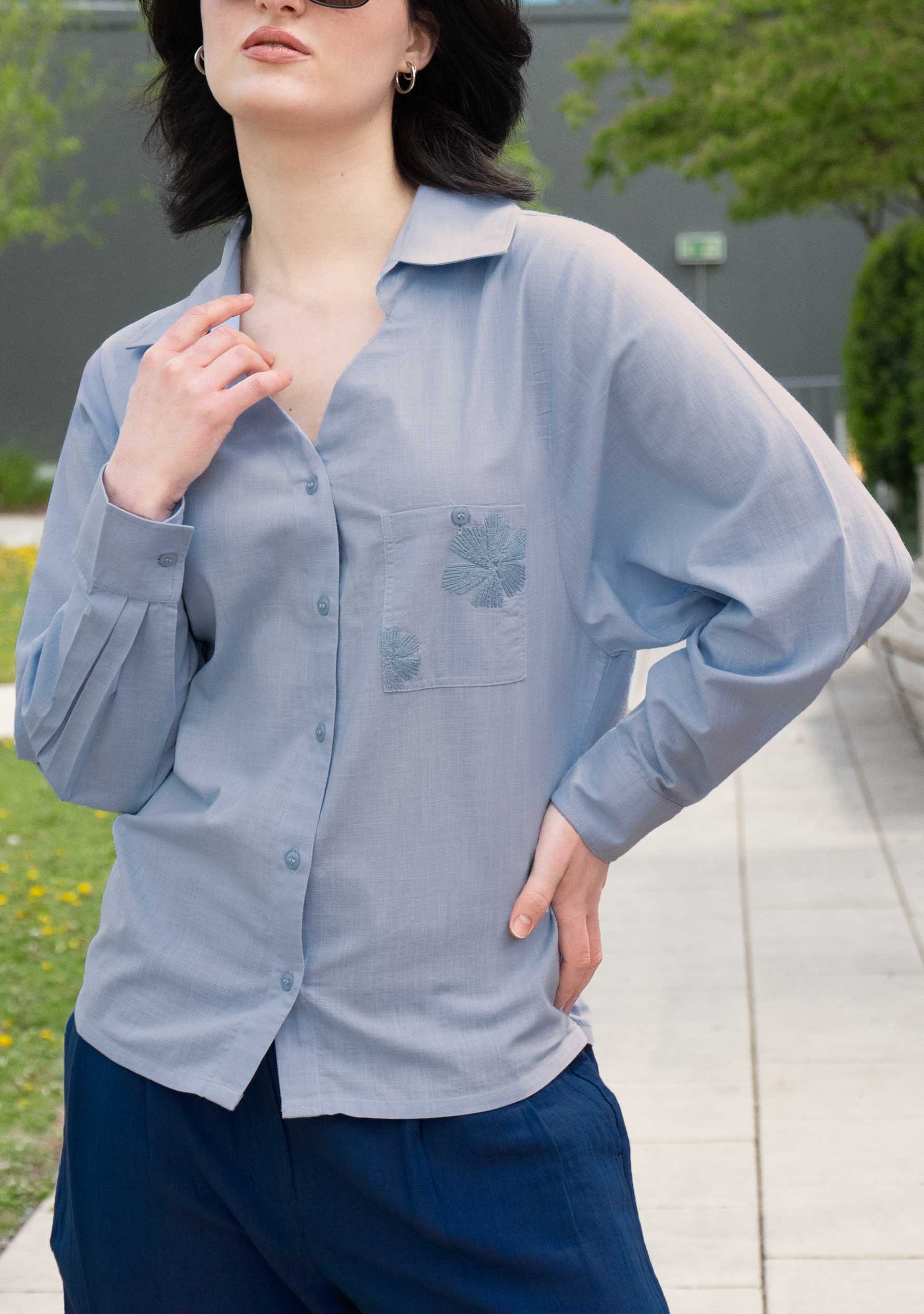 Woman wearing a powder blue handloom cotton shirt with navy linen trousers, modern smart casual outfit; Frau in hellblauer Bluse aus handgewebter Baumwolle und marineblauer Leinenhose, moderner Smart-Casual-Look