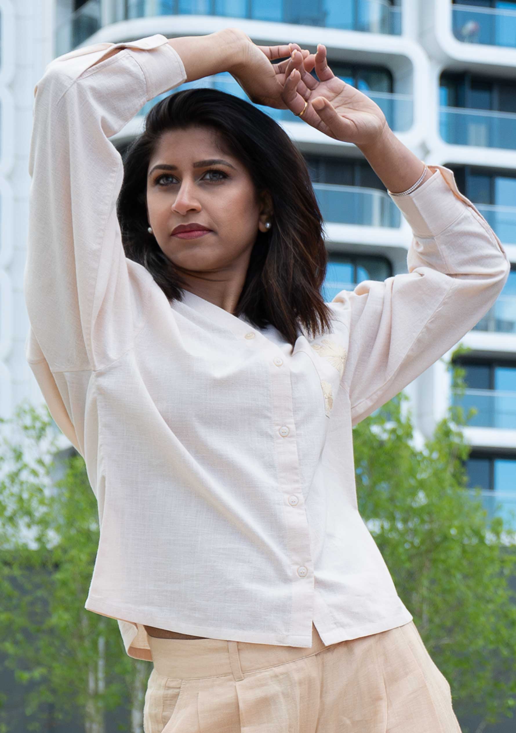 Woman wearing a beige handloom cotton shirt with cream linen trousers, smart casual sustainable outfit; Frau in beiger Bluse aus handgewebter Baumwolle und cremefarbener Leinenhose, Smart-Casual-Look in Naturfasern